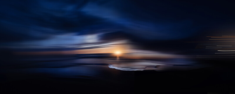 Blurred sunset over a dark landscape with golden sun and streaking clouds in blue twilight.