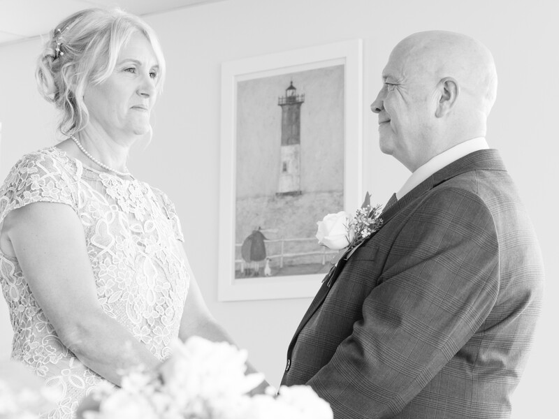 Bride and groom face each other during a wedding ceremony, shot in black and white.