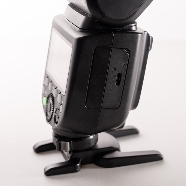 External camera flash unit shown from rear angle with stand and diffuser visible.