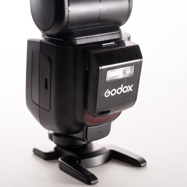 Godox camera flash mounted on a stand with a metallic reflector attachment on top.