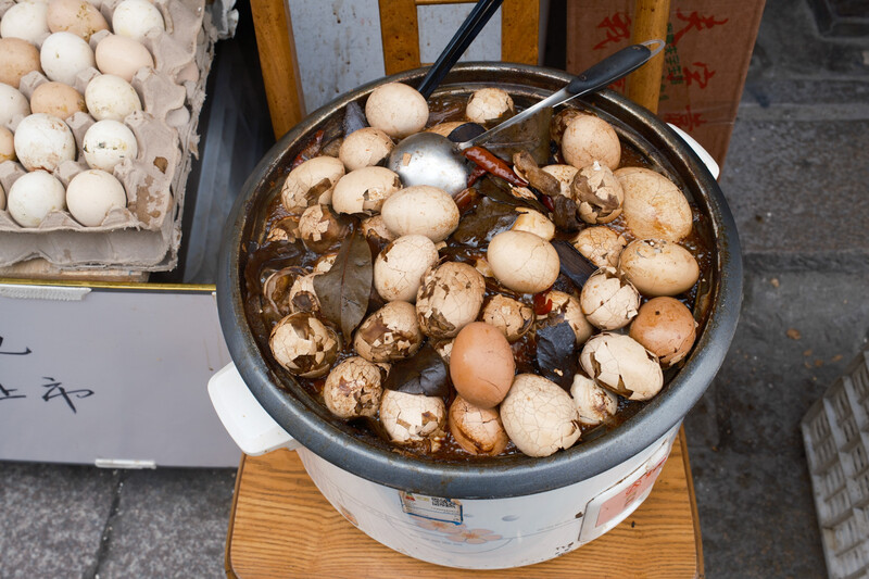 Pot of mushrooms cooking in broth with various sizes and colors of fungi visible.