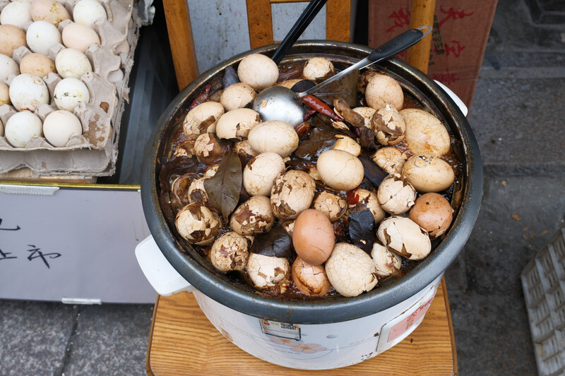Pot of mixed mushrooms and other ingredients simmering in broth on a wooden base.