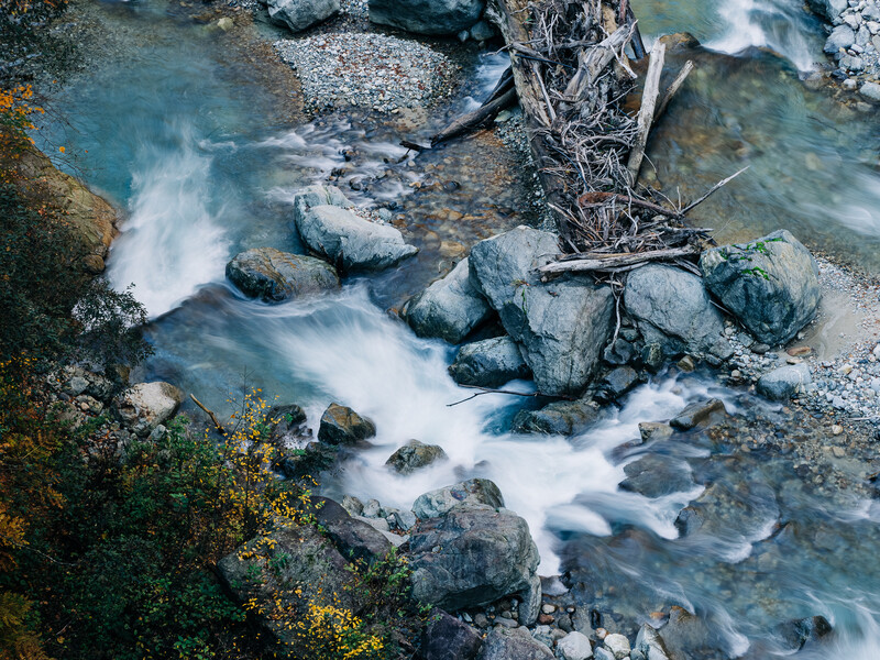 Fast-flowing mountain stream with smooth water cascading over moss-covered rocks and boulders.