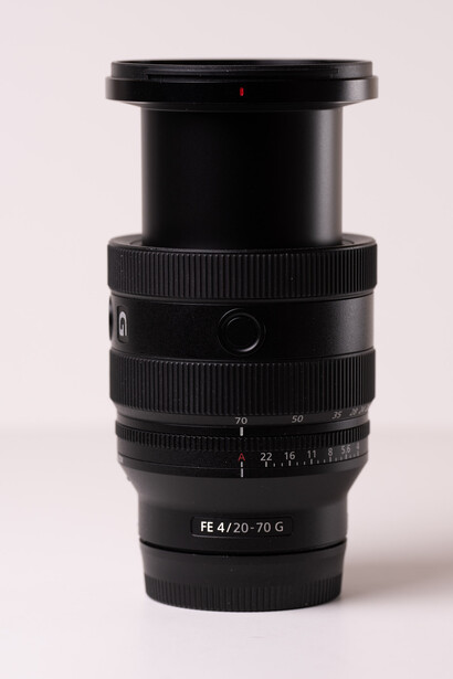 Sony FE 4/25-70mm zoom lens with black barrel and focus ring against neutral background.