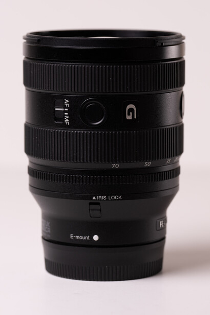 Black telephoto zoom lens with focus ring, aperture markings, and autofocus switch against neutral background.