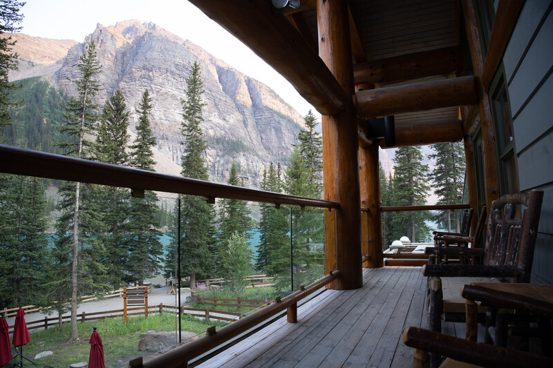 Modern glass-railed deck extending toward forested mountain landscape with snow-capped peak.