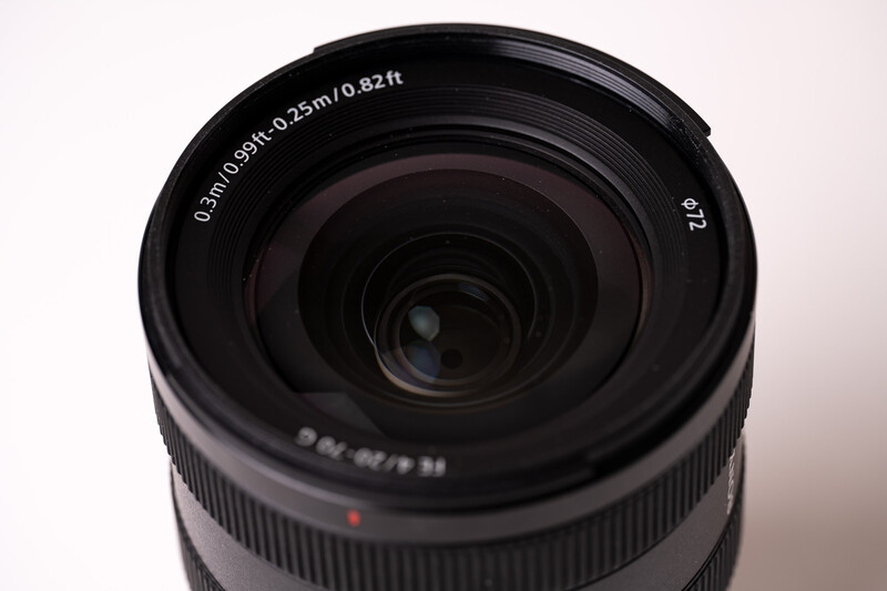 Wide-angle camera lens with visible aperture and focusing elements against neutral background.