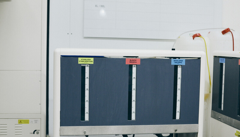 Laboratory analyzer with three labeled sample slots on dark panel and connected tubing.