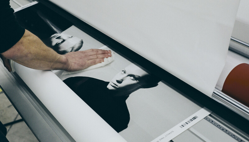 Photographer's hand hovering over black and white portrait prints on a lightbox during image review.