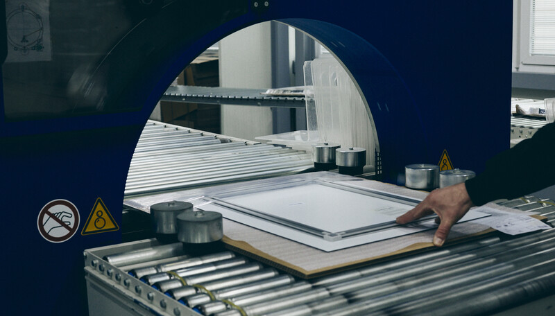 Large format printing or cutting machine with white material loaded on conveyor rollers and circular opening visible from above.