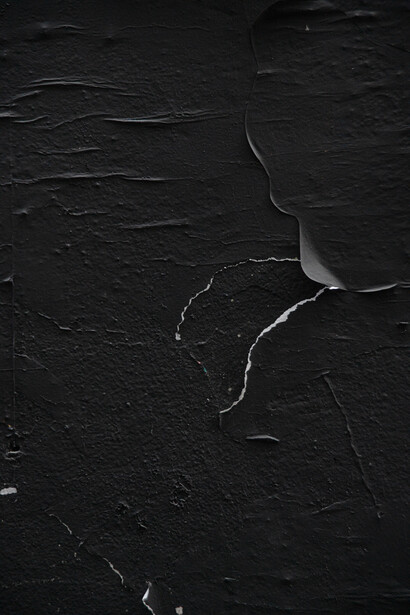 High-contrast black and white photograph of cracked earth or dried mud surface with white lines marking fissures.