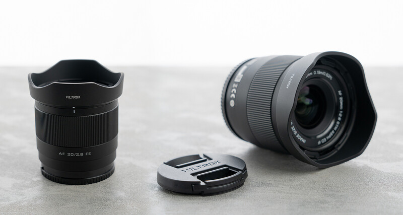 Three camera lenses and a lens cap arranged on a concrete surface.