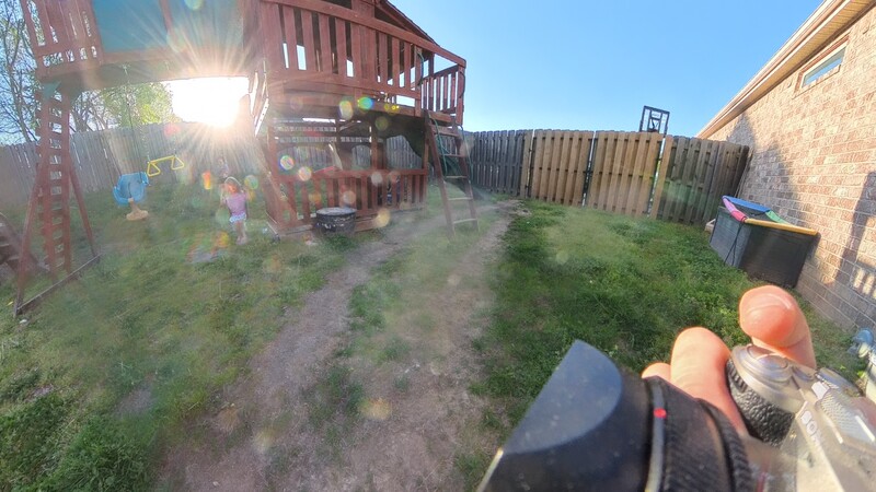 First-person view from horseback in a backyard with a wooden play structure and fence.