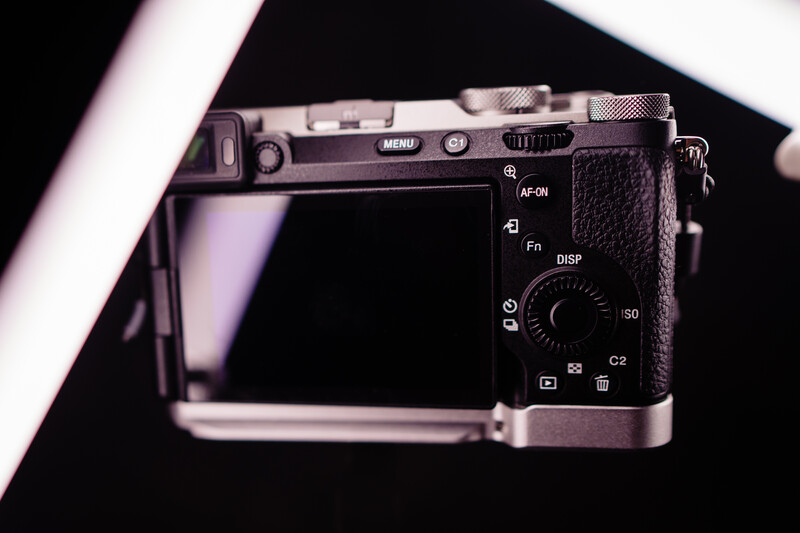 Top-down view of a compact mirrorless camera with articulating LCD screen and control buttons visible.