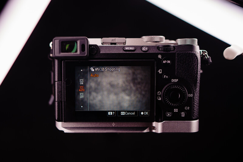 Mirrorless camera displayed from above with rear LCD screen active, showing menu interface and controls.