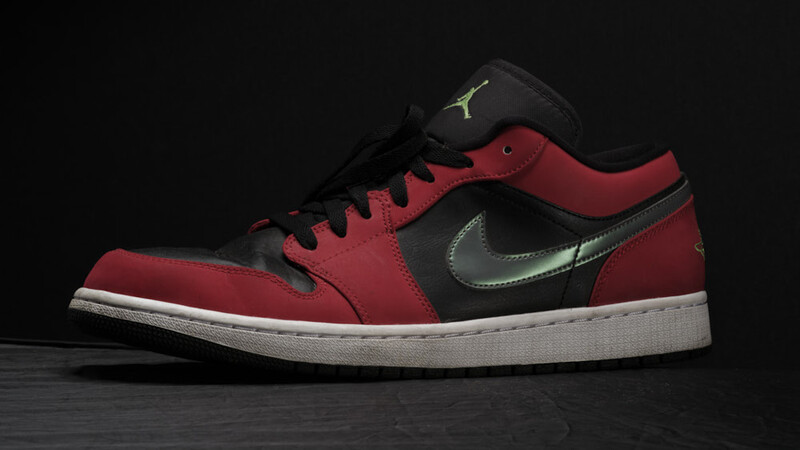 Low-top sneaker with burgundy and black colorblocking, white midsole, and metallic swoosh against dark background.