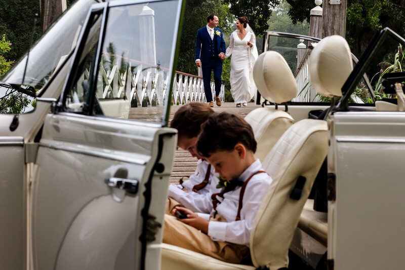 Child in car interior with wedding couple visible in background near vehicle entrance.
