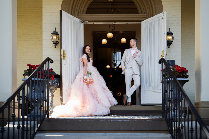 Bride and groom exiting a columned doorway on their wedding day.