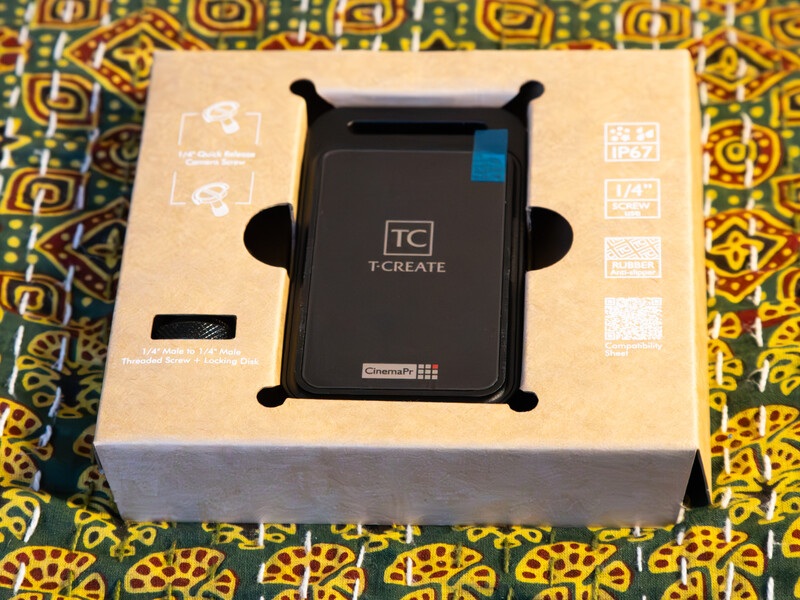Unboxing of a TC CREATE mobile phone holder in its packaging with colorful patterned background.