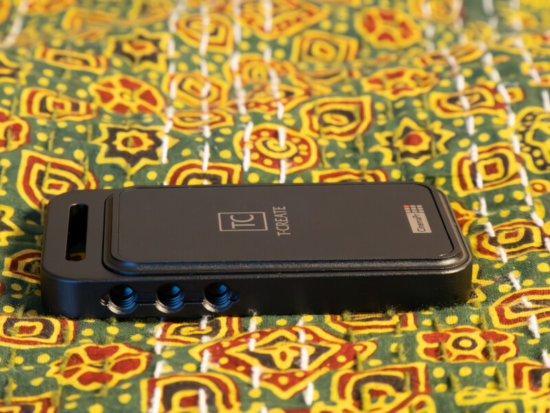 A black smartphone with blue accents laid on a colorful patterned fabric with yellow and green geometric designs.