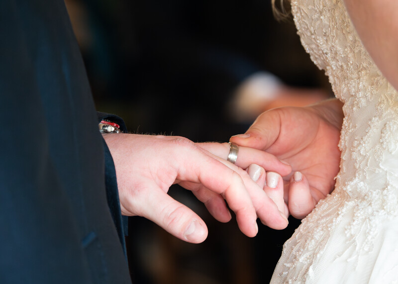 Bride and groom exchanging rings during wedding ceremony, hands joined together.