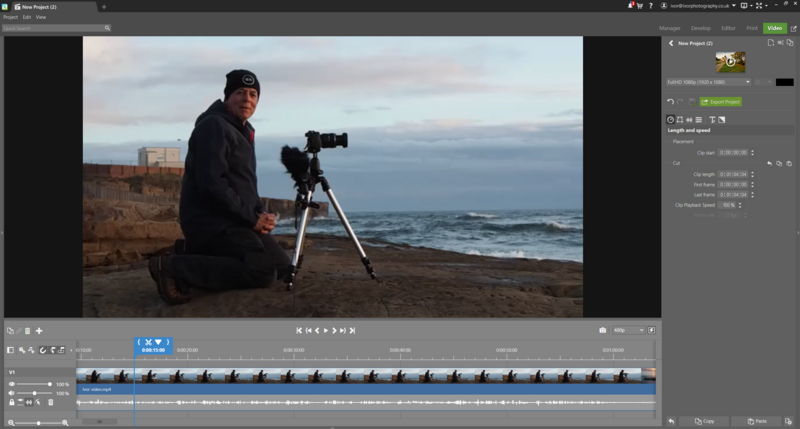 Photographer with telephoto lens on tripod positioned on rocky beach overlooking ocean.