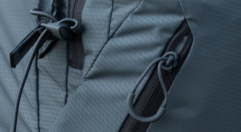 Close-up of gray fabric with black cord drawstrings and toggle fasteners on a jacket or bag.