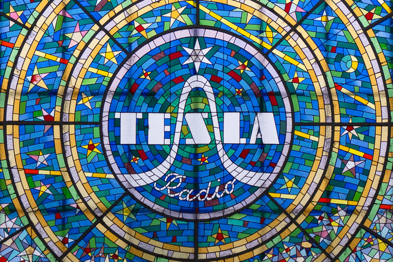 Stained glass window with concentric circular design featuring blue background, gold borders, stars, and central text reading 'TEAL Radio'.