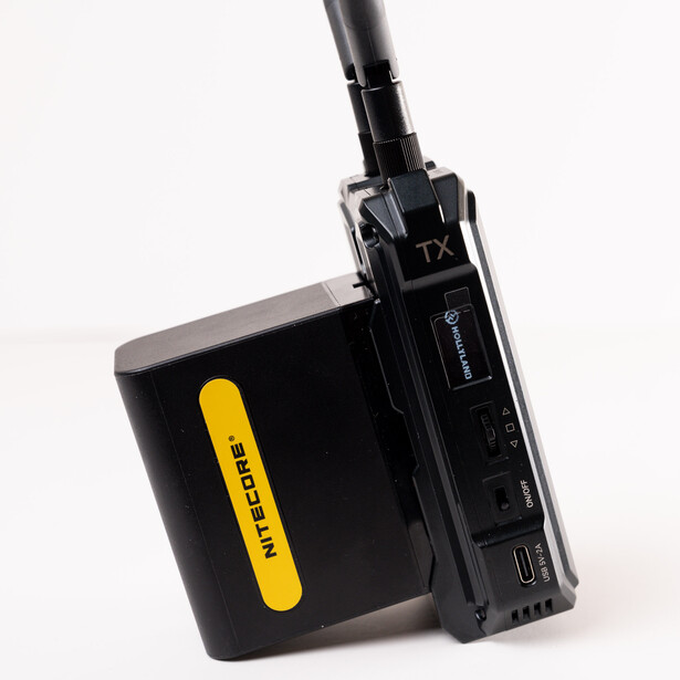 Professional wireless microphone transmitter and battery pack displayed against white background.
