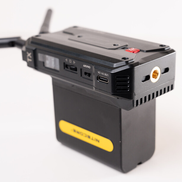 Portable power station with antenna and multiple connection ports mounted on yellow battery base.