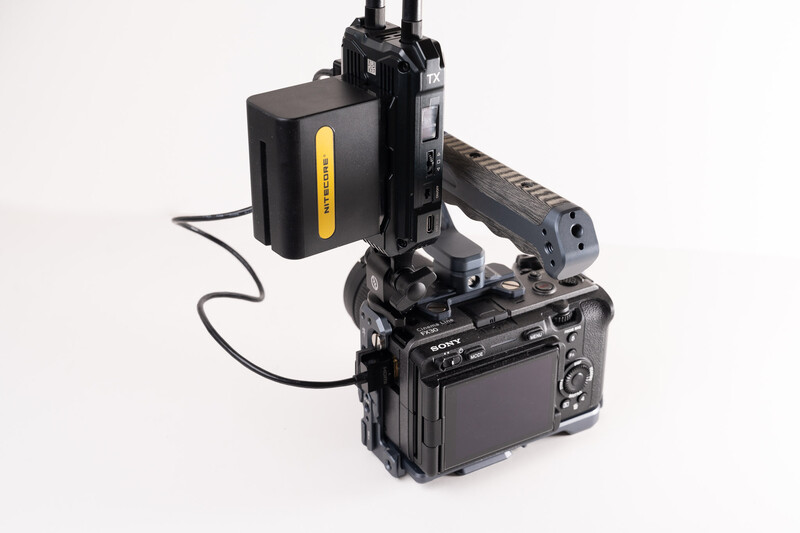 Professional video camera setup with external monitor, battery pack, and articulating arm mounted on white background.