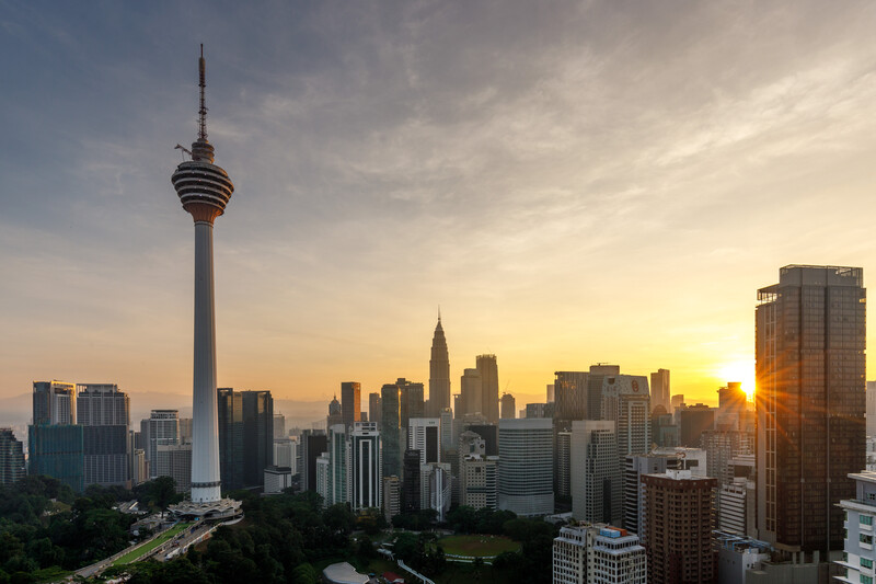 Cityscape with communications tower at golden hour sunset, surrounded by high-rise buildings.