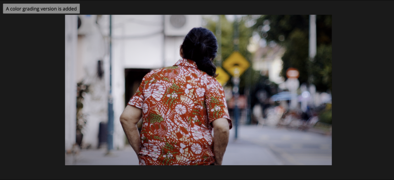 Man wearing red and white floral shirt walking away down a blurred urban street.
