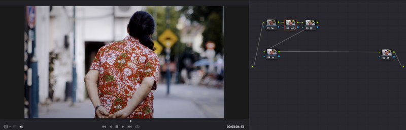 Person wearing red patterned shirt photographed from behind on a city street.