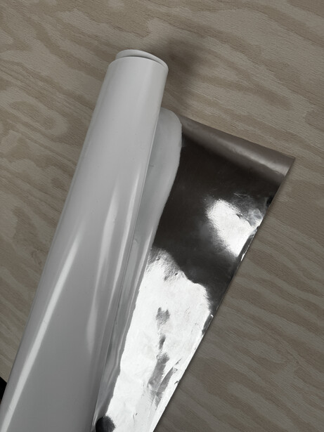 White reflector and black reflector leaning against wooden floor backdrop.