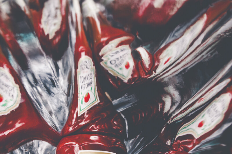 Close-up overhead view of red tomato cans with white labels arranged on a dark surface.