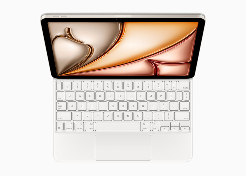 Overhead view of a white laptop displaying abstract orange and bronze flowing shapes on its screen.