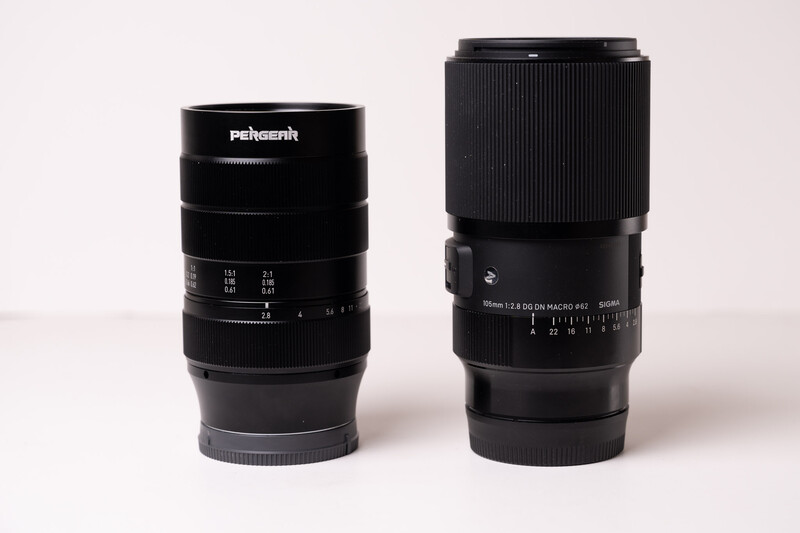 Two black telephoto lenses side by side against a neutral background.