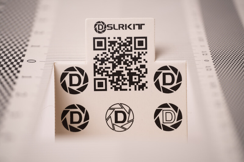 QR code and logo design sheet with SLRKIT branding and circular aperture motifs on textured background.