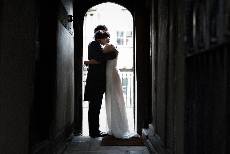 Couple embracing in a narrow dark passageway with bright daylight visible at the opening ahead.