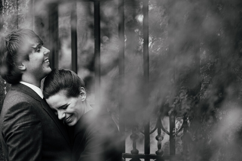Man and woman embrace against a weathered wall in black and white portrait photography.