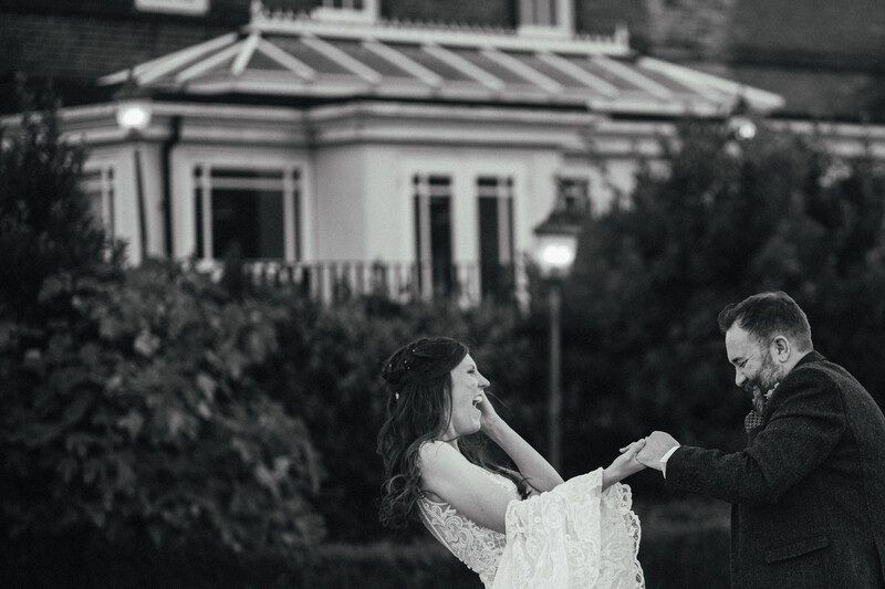 Couple dancing outdoors at night in front of an illuminated house.