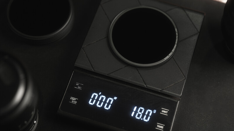Digital scale displaying 0.00g and 180° measurements with lens filters positioned on dark surface.