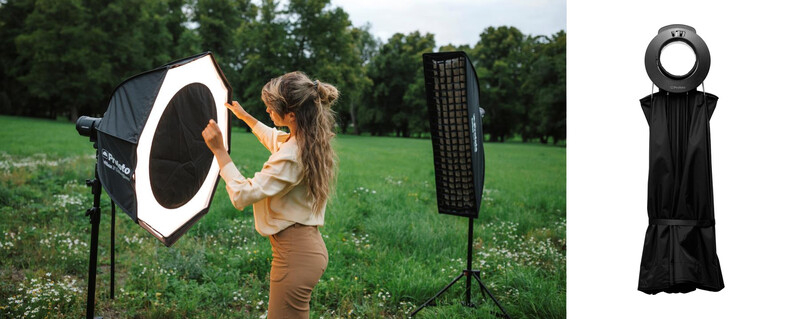 Photographer holding a large octagonal softbox modifier while positioning it toward the camera in an outdoor field setting.