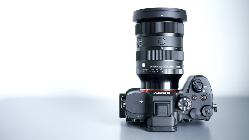 Sony mirrorless camera body with large telephoto lens mounted on white surface.