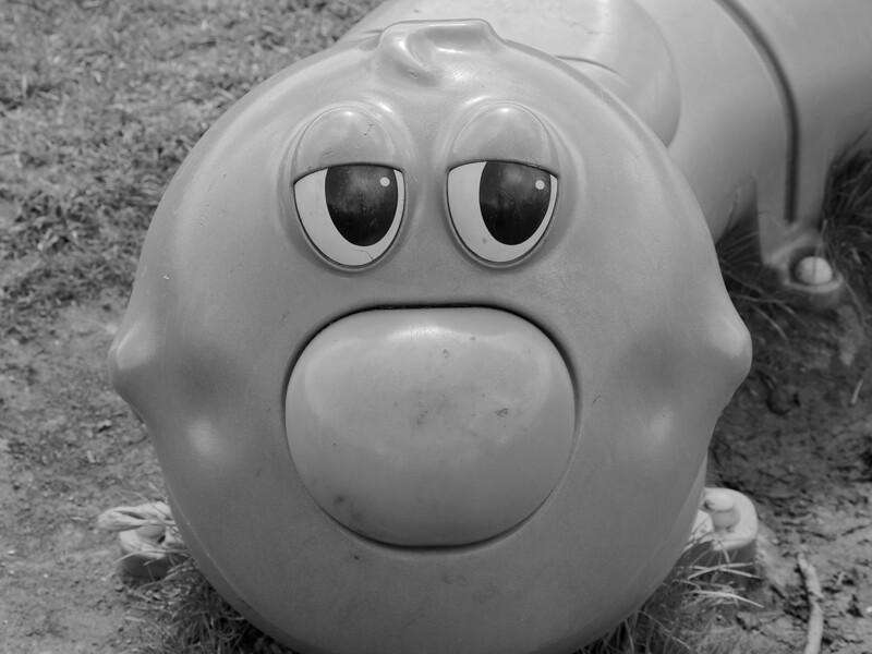 Black and white photograph of a round character toy with exaggerated facial features and a sad expression.