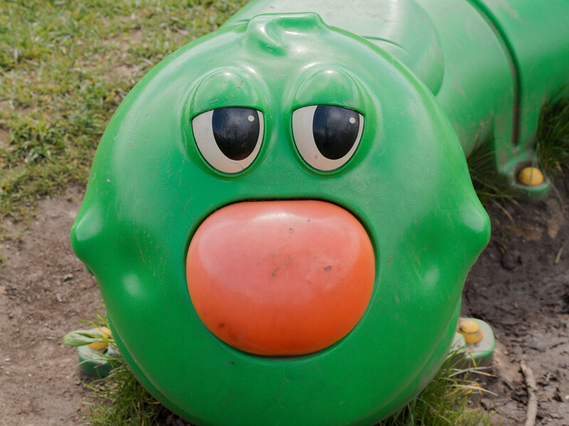 Close-up of a green toy train engine with large cartoon eyes and a bright red circular mouth.
