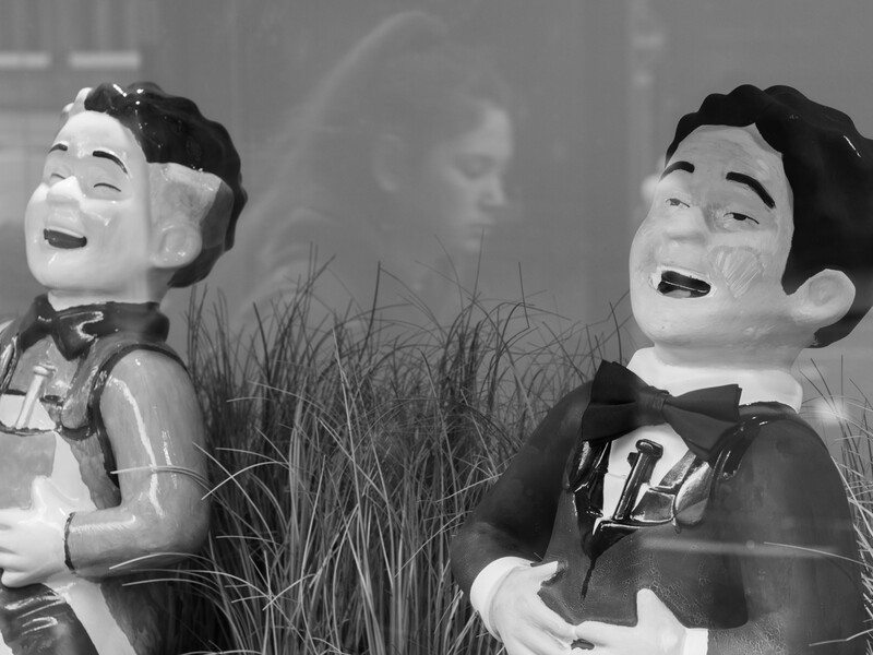 Two vintage dolls with exaggerated smiling expressions and dark hair, positioned against a blurred background.