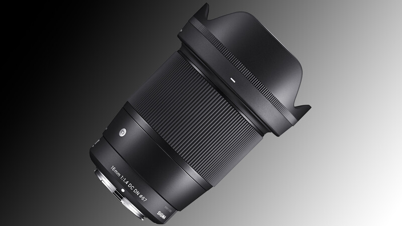 Wide-angle zoom lens with lens hood attached, displayed at an angle against a gradient gray background.