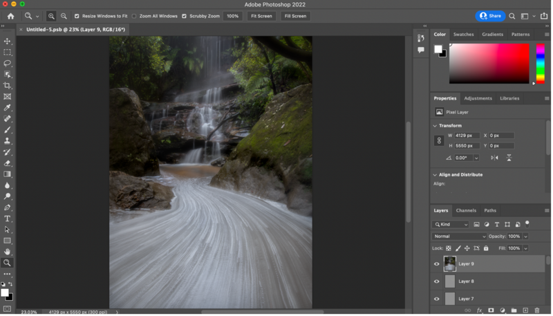Long-exposure photograph of a cascading waterfall with silky water flow and moss-covered rocks in a forested ravine.